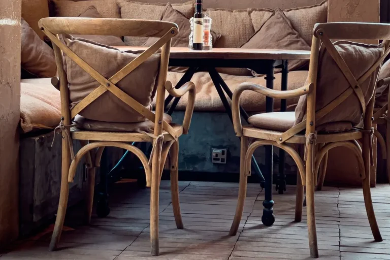 Restaurant table with a metal base, two wooden armchairs and a cushioned banquette