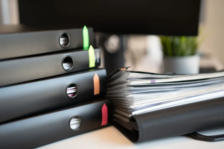 Stacked office binders with colour tabs on a desk