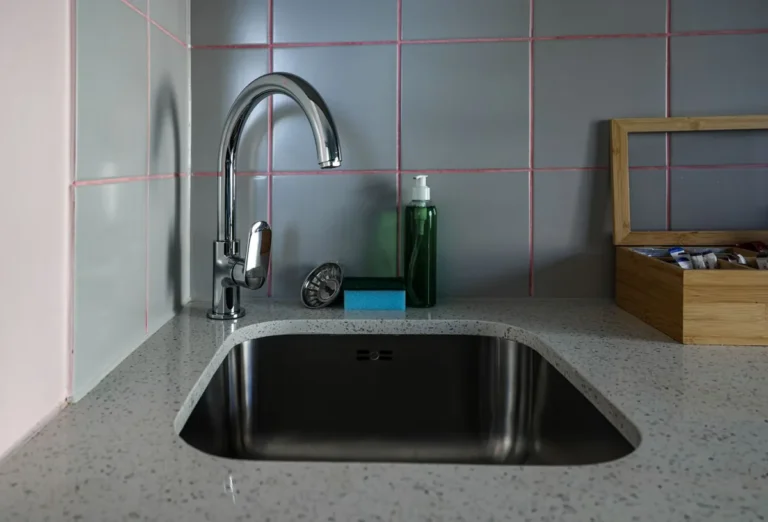 Stainless steel undermount kitchen sink in a stone benchtop with a chrome tap