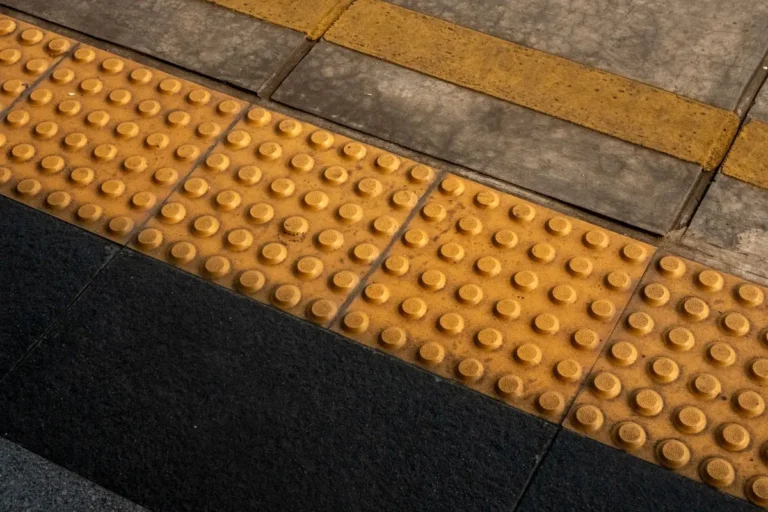 Tactile paving tiles with raised studs at the edge of a pavement