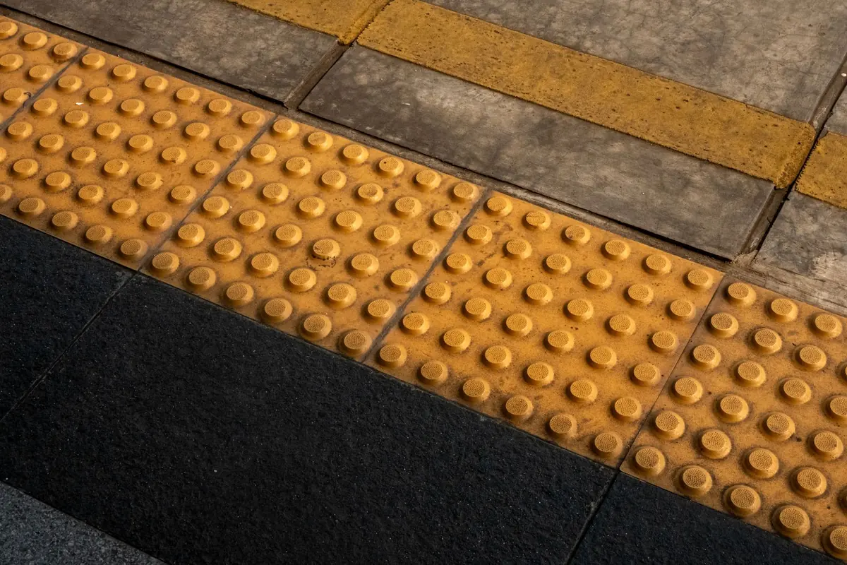 Tactile paving tiles with raised studs at the edge of a pavement