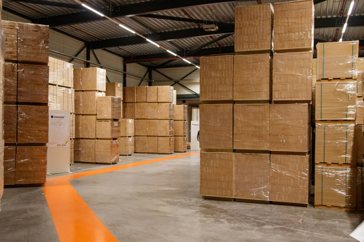 Warehouse aisle with wrapped cartons stacked on pallets and an orange floor marking