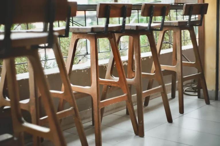 Row of wooden bar stools with backs along a window counter