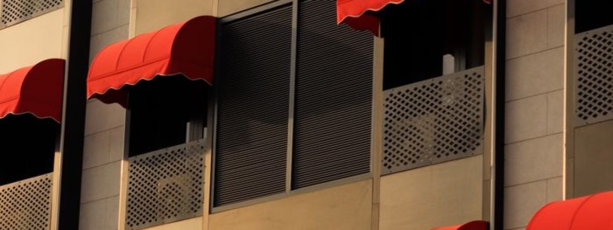 Vertical shot of a building facade in Ankara featuring red awnings and windows.