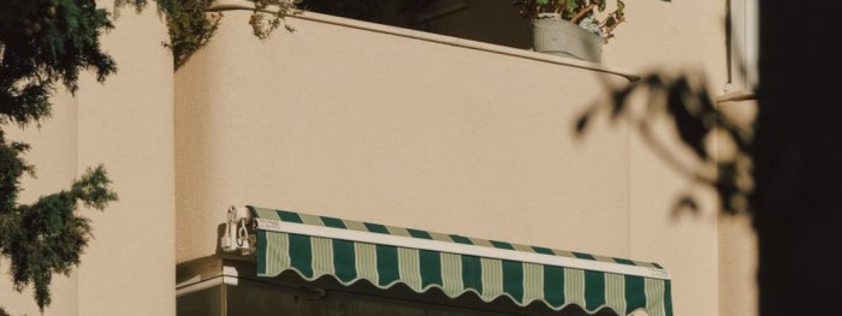 View of a city apartment's facade with green-striped awnings and balconies.