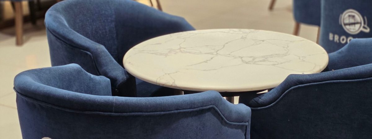 Stylish cafe setting with a marble table surrounded by blue chairs labeled Brooklyn.
